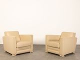 deux fauteuils en cuir beige placés l'un à côté de l'autre sur un sol en béton