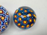 two glass paperweightes sitting on a white surface
