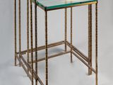 a pair of brass and glass nesting tables on a white background