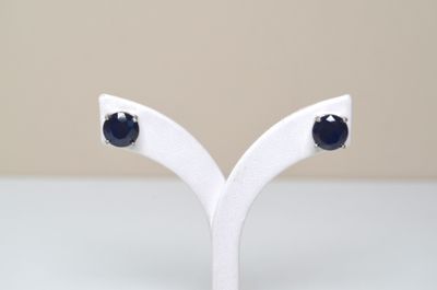 une paire de boucles d'oreilles à clous en saphir noir, présentées sur un socle blanc