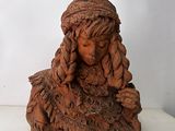 statue d'une femme aux cheveux longs assise sur une surface blanche