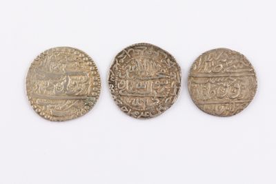 three silver coins sitting next to each other on top of a white surface