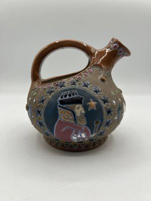 a small ceramic jug with a picture of a man on it