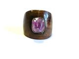 une image représentant une bague en bois ornée d'une pierre violette au centre
