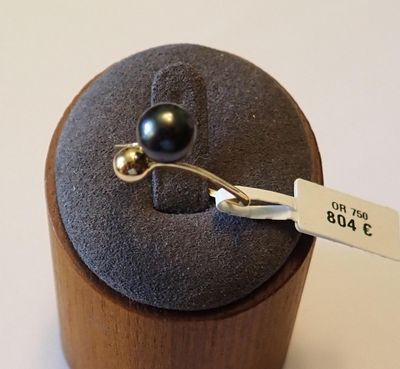 une bague sertie d'une perle noire, posée sur un coffret en bois