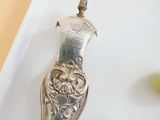a silver spoon sitting on top of a white plate with grapes