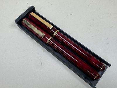 deux stylos rouges dans une boîte noire posée sur une surface blanche
