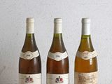 trois bouteilles de vin sont alignées sur une table en bois