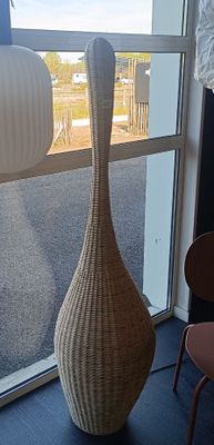 un grand vase posé devant une fenêtre