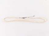 un collier de perles blanches avec un fermoir en argent sur fond blanc