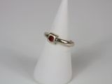 a close up of a ring on a white cone with a red stone