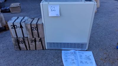 un réfrigérateur blanc posé à même le sol, à côté d'une pile de cartons