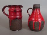 two red and black vases sitting next to each other