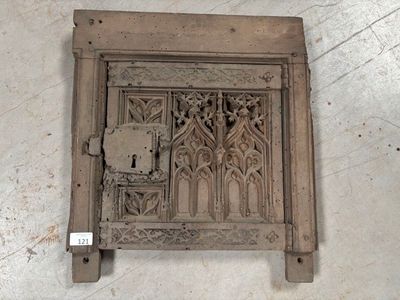 une porte en bois posée par terre, sur laquelle est accrochée une horloge