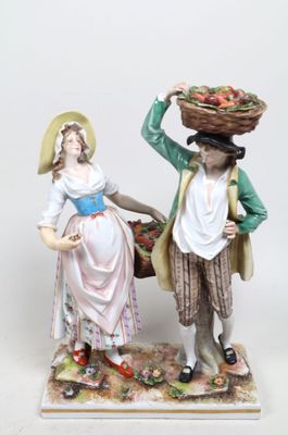 une figurine représentant un homme et une femme portant des paniers sur la tête