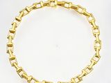 gros plan d'un bracelet en or sur une surface blanche