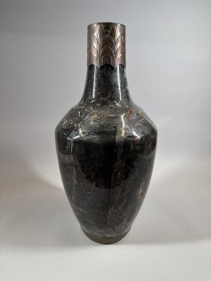 an old black vase sitting on top of a white table