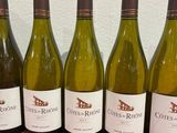 six bottles of white wine are lined up on a table
