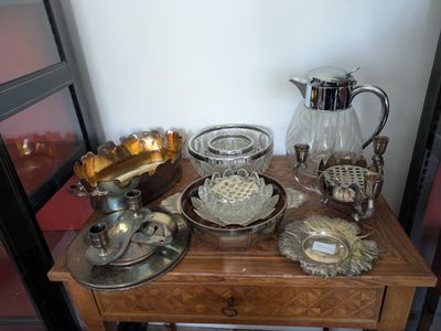 une petite table sur laquelle sont disposés de nombreux objets en argent et en verre