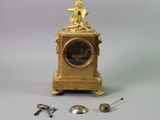 a gold clock with a figurine sitting on top of it