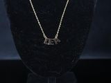 a gold necklace with two letters on a black mannequin
