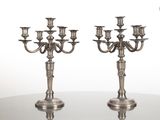 paire de chandeliers anciens en métal argenté posés sur une table en verre