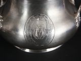 a silver vase with a lion on it on a black background