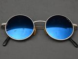 lunettes de soleil argentées aux verres bleus, posées sur une surface grise