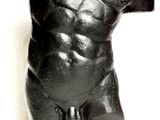 une sculpture noire représentant un torse masculin posée sur un socle noir