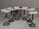 six tabourets sont disposés en cercle sur un fond gris