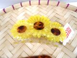 two pieces of plastic sunflower hair clips on a woven basket