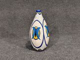 un vase blanc orné de motifs bleus et jaunes