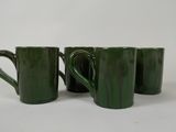 quatre tasses à café vertes sont alignées sur une surface blanche