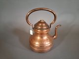 a small copper tea kettle on a gray surface