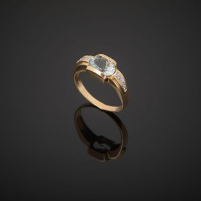 a gold ring with a blue topaz stone and diamonds on a black surface