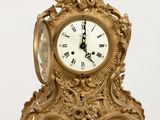 a gold clock sitting on top of a wooden table