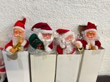 five santa claus figurines in a row on a shelf
