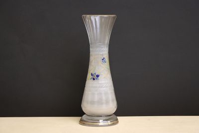 un vase en verre posé sur une table, avec un mur noir en arrière-plan