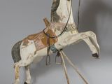 un petit cheval en bois avec une selle sur le dos
