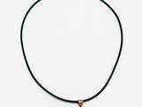 un collier composé d'un cœur en pierre verte monté sur un cordon noir