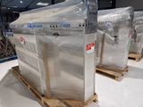 three large televisions wrapped in plastic sitting on pallets in a warehouse