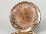 a gold plated pocket watch sitting on a white surface