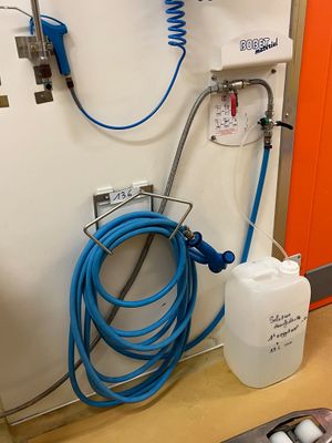 un tuyau bleu fixé au mur, à côté d'un récipient blanc