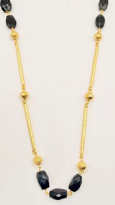 a black and gold necklace with beads on a white background