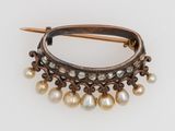 a close up of a broochle with pearls on a white surface