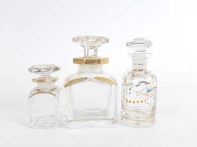 trois bouteilles en verre transparent ornées de bordures dorées et d'un bouchon doré