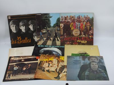 Les albums des Beatles sont posés sur une table devant un fond blanc.