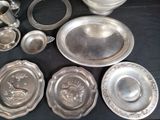a lot of silver plates and bowls on a table
