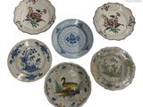 quatre assiettes à motifs différents posées sur une surface blanche