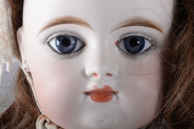 a close up of a doll ' s face with blue eyes
